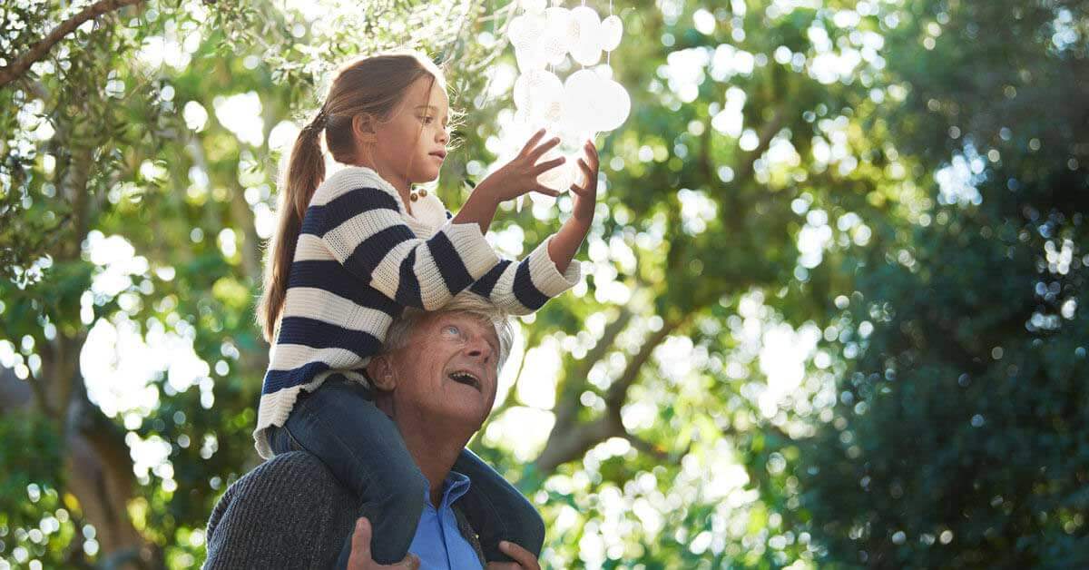 Il nonno tiene in braccio la nipote sulle spalle.