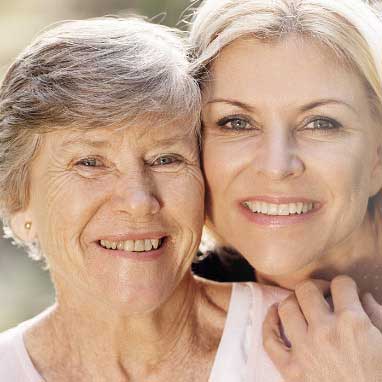 zwei ältere Frauen schauen glücklich in die Kamera