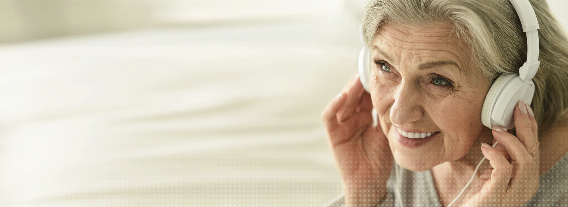 eine ältere Frau hört mit ihren Kopfhörern