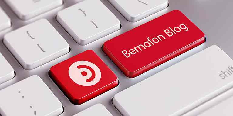 Bild på vitt tangentbord med två flikar ändrat till rött med Bernafons logotyp och texten Bernafon blogg