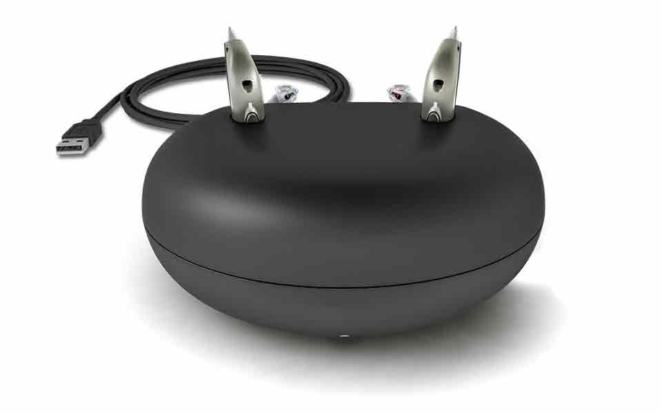 Bernafon Viron miniRITE T R høreapparater med genopladeligt litium-ion-batteri placeret i bordladeren med strømkabel i baggrunden