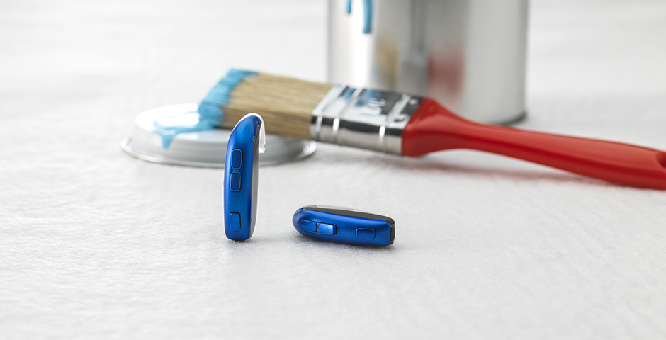L'aide auditive derrière l'oreille Bernafon Leox Super Power | Ultra Power avec un pinceau rouge et un bidon bleu.