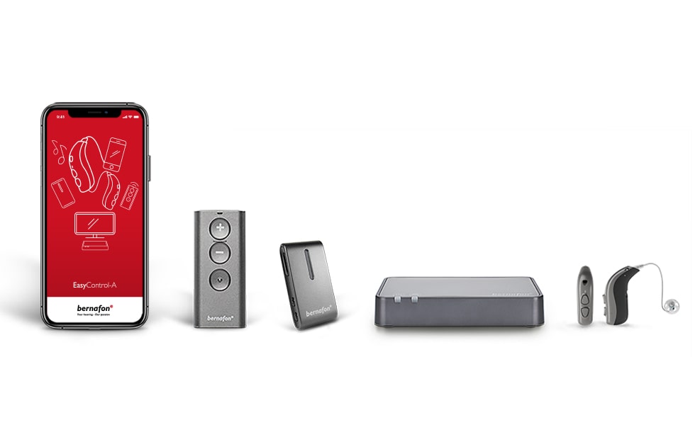 Accesorios Bernafon alineados, incluida la aplicación Bernafon en un smartphone, adaptador de TV, control remoto, audífonos y Soundclip-A