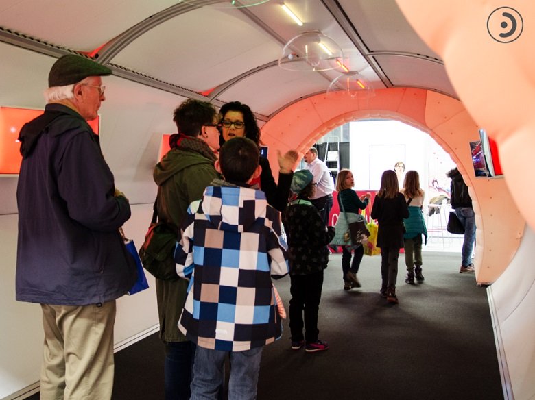 Adults and children walking through the Bernafon tunnel at an annual fair. Hearing aid expert answers questions about hearing.
