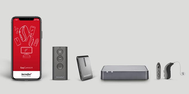 Bernafon tillbehör på rad, inklusive Bernafon app på en smartphone, TV-adapter, fjärrkontroll, hörapparater och Soundclip-A