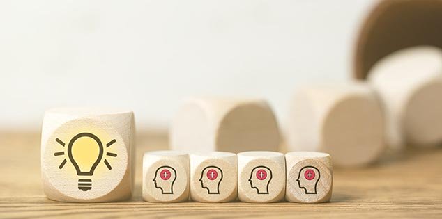 Five dice lined up in a row illustrate product training, the biggest has an illustration of a light bulb and the other four have the outline of a head