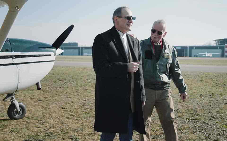Пользователь слухового аппарата Bernafon и пилот Джон, выходящий из своего маленького самолета после полета со своим вторым пилотом