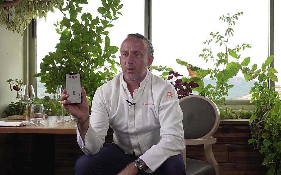 Bernafon Hörgeräteträger, Chefkoch Jean-François, hält sein Smartphone mit der Bernafon App geöffnet hoch