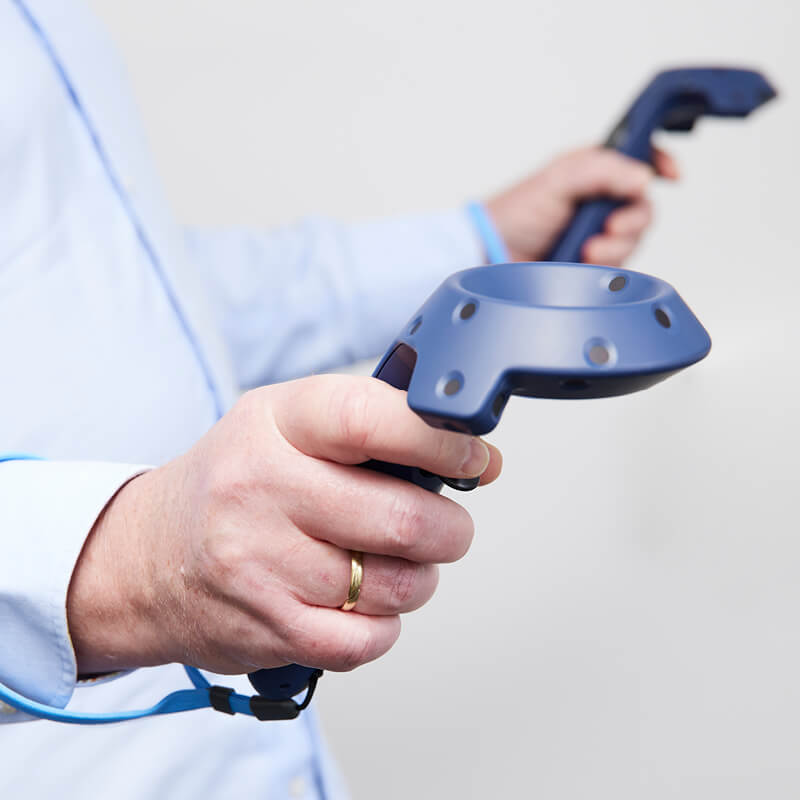 Un hombre anciano sujetando el dispositivo BalanceVR en sus manos.