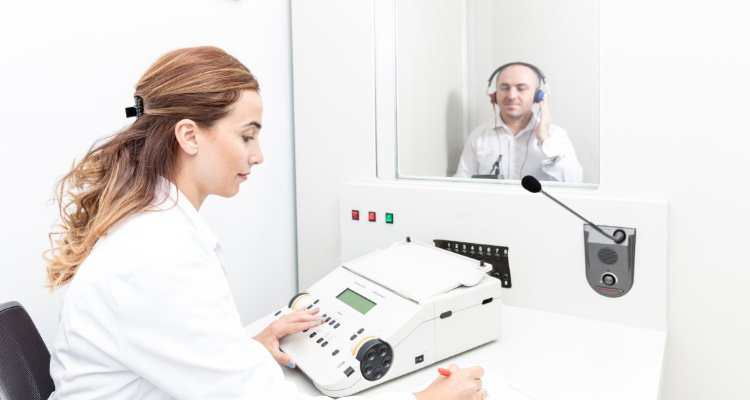 Hearing specialist performing a hearing screening. Hearing specialists explain about best hearing aid solution and prices.