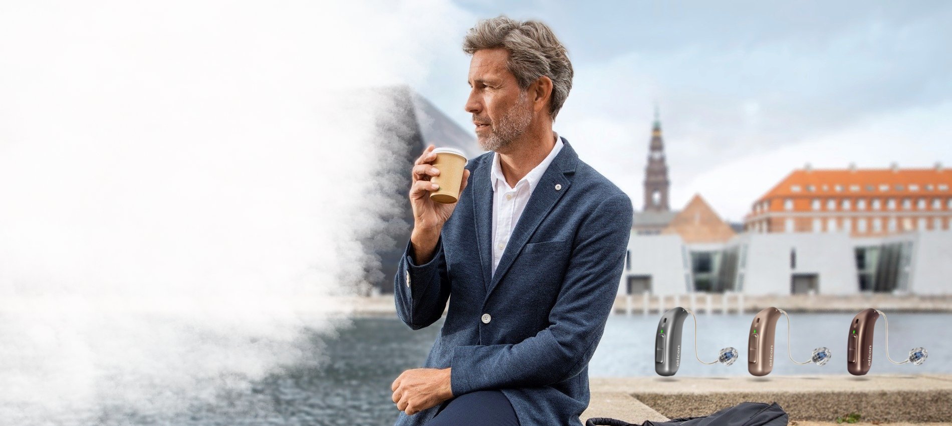 un homme qui porte un appareil auditif qui boit un café au bord d'une rivière