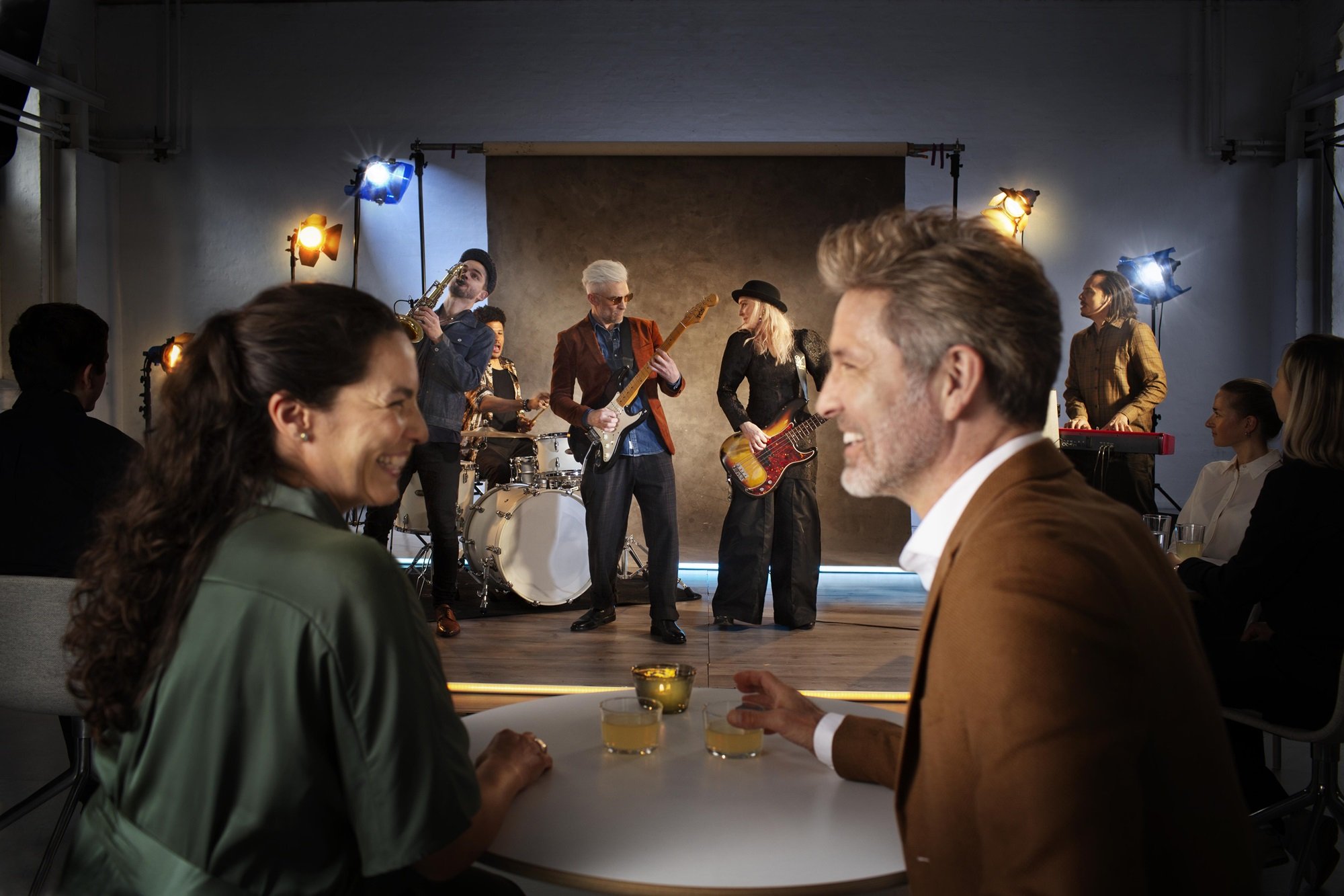 Un homme et une femme boivent un verre avec un groupe de musique en arrière plan