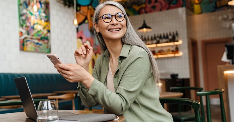 Femme avec son téléphone et son ordinateur dans un café