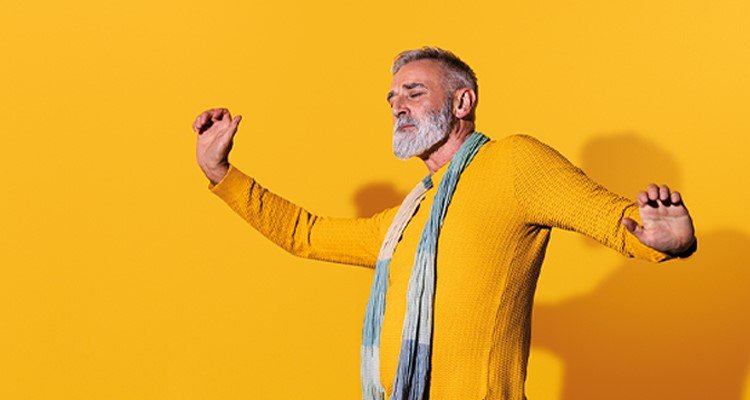 Ein Mann mittleren Alters, der Philips HearLink Hörgeräte trägt, tanzt und fühlt sich selbstbewusst.