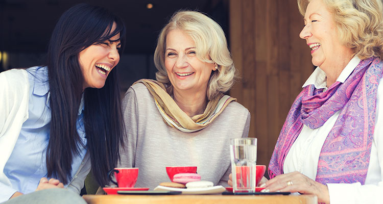 Drei Frauen, die es genießen, Zeit in einem Café im Freien zu verbringen und sich ohne Schwierigkeiten unterhalten.