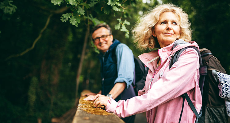 Mann und Frau wandern durch Wald und genießen die Klänge der Natur