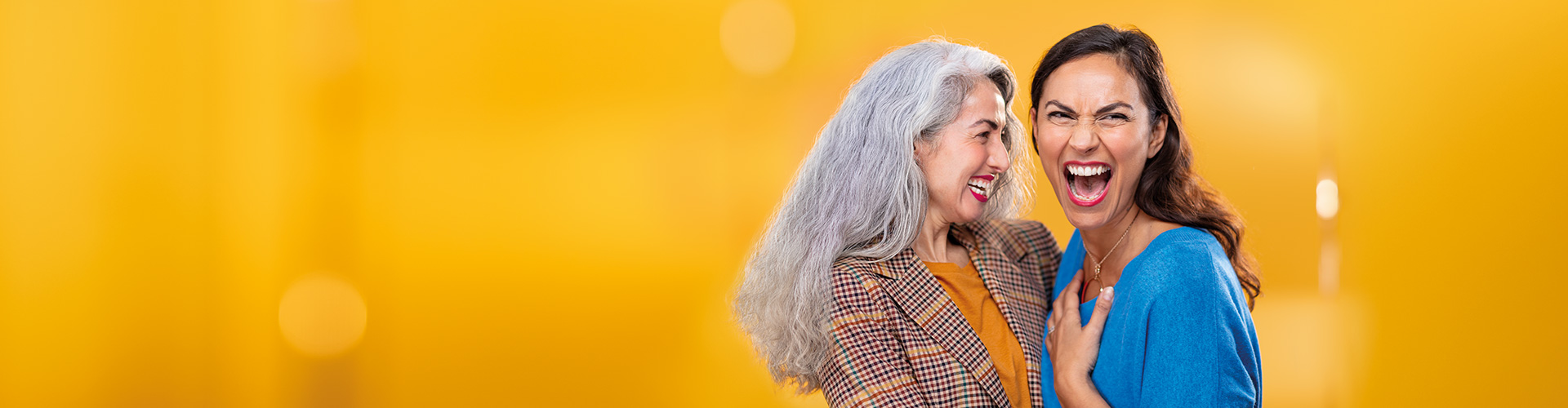 Two middle-aged women hugging each other. One is wearing Philips HearLink in-the-ear hearing aids.