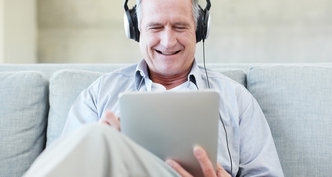 Hombre sentado en el sofá comprobando su audición con la prueba de audición en línea. 