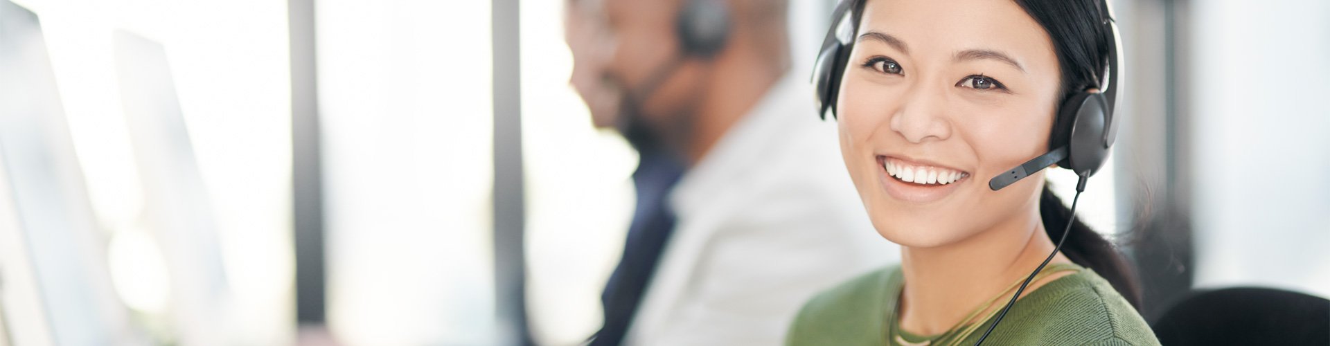 Femme parlant au téléphone et apportant de l’aide à un client avec ses prothèses auditives. 