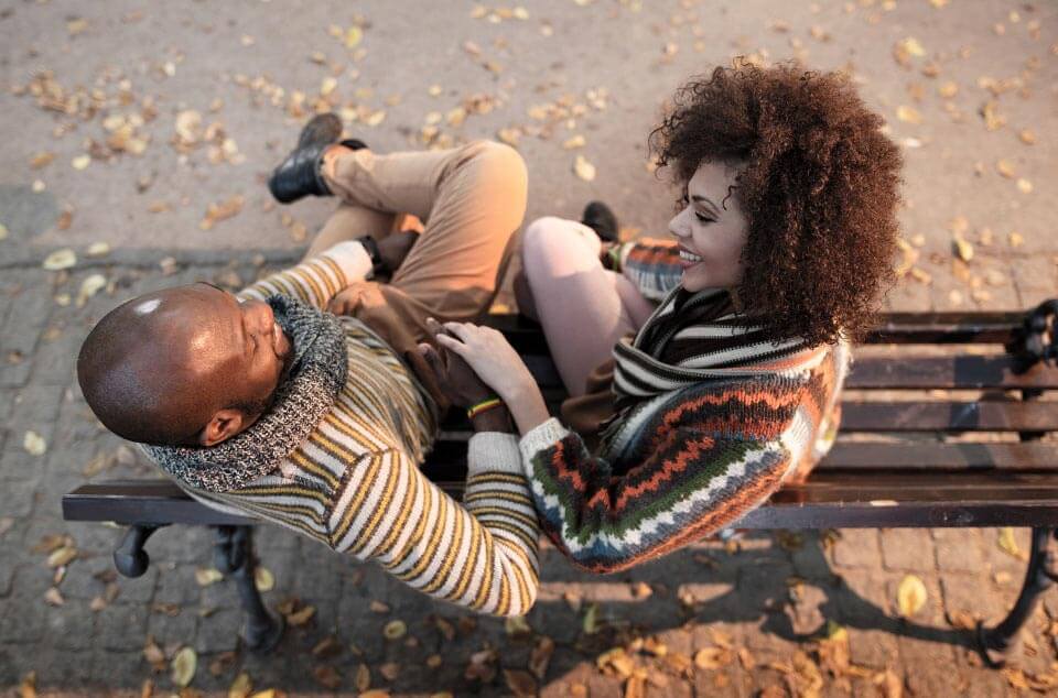 Un jeune couple assis sur un banc dans le parc