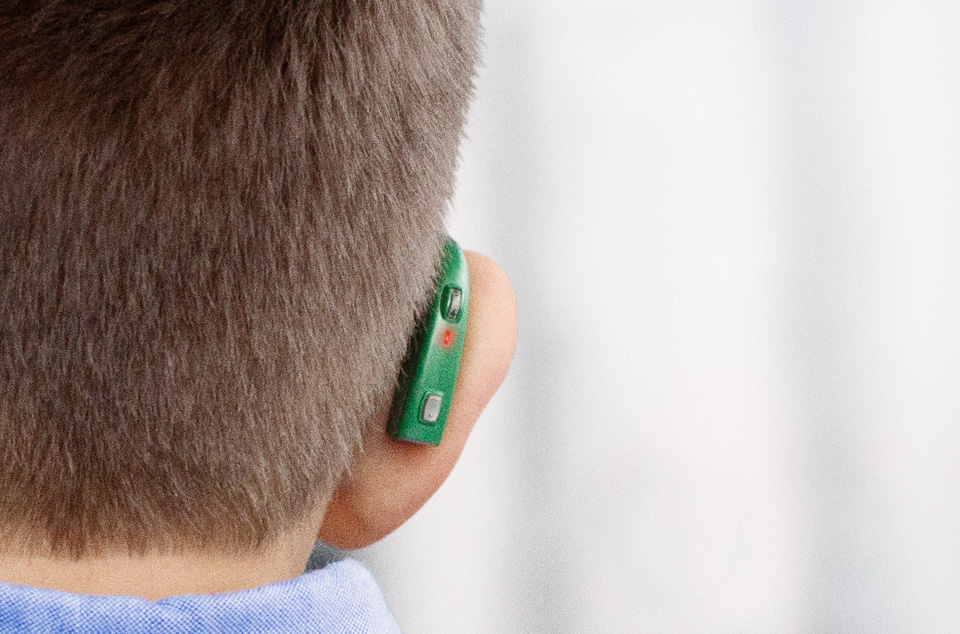gros plan de dos oreille enfant avec appareil auditif vert