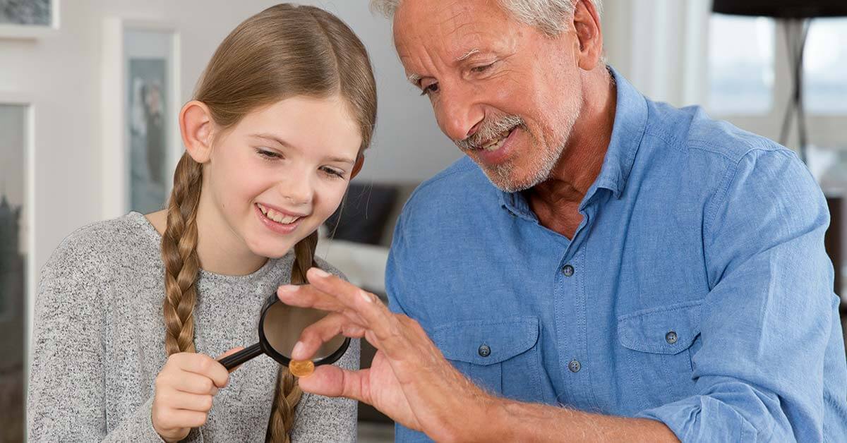 Grossvater mit Enkelin schauen sich Goldmuenzen an