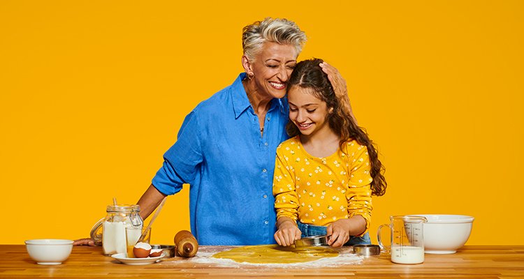 Een oma die Philips HearLink draagt en geniet van een kostbaar moment met haar kleindochter die koekjes bakt.