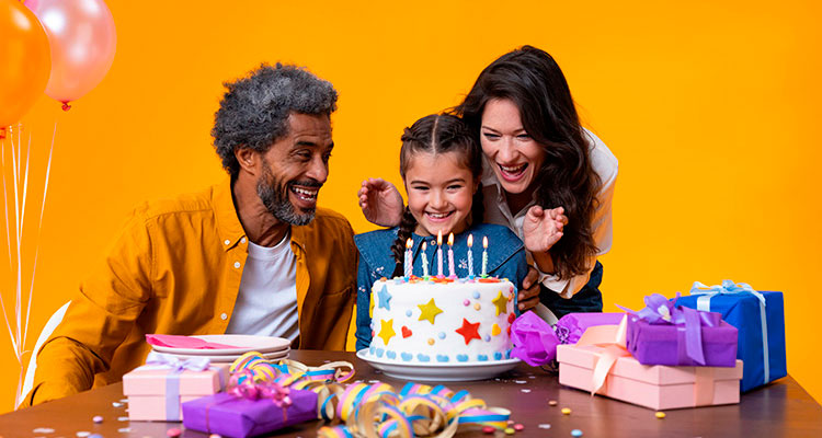Grandfather with Philips HearLink hearing aids and his daughter celebrate his granddaughter's birthday with cake, balloons and gifts.