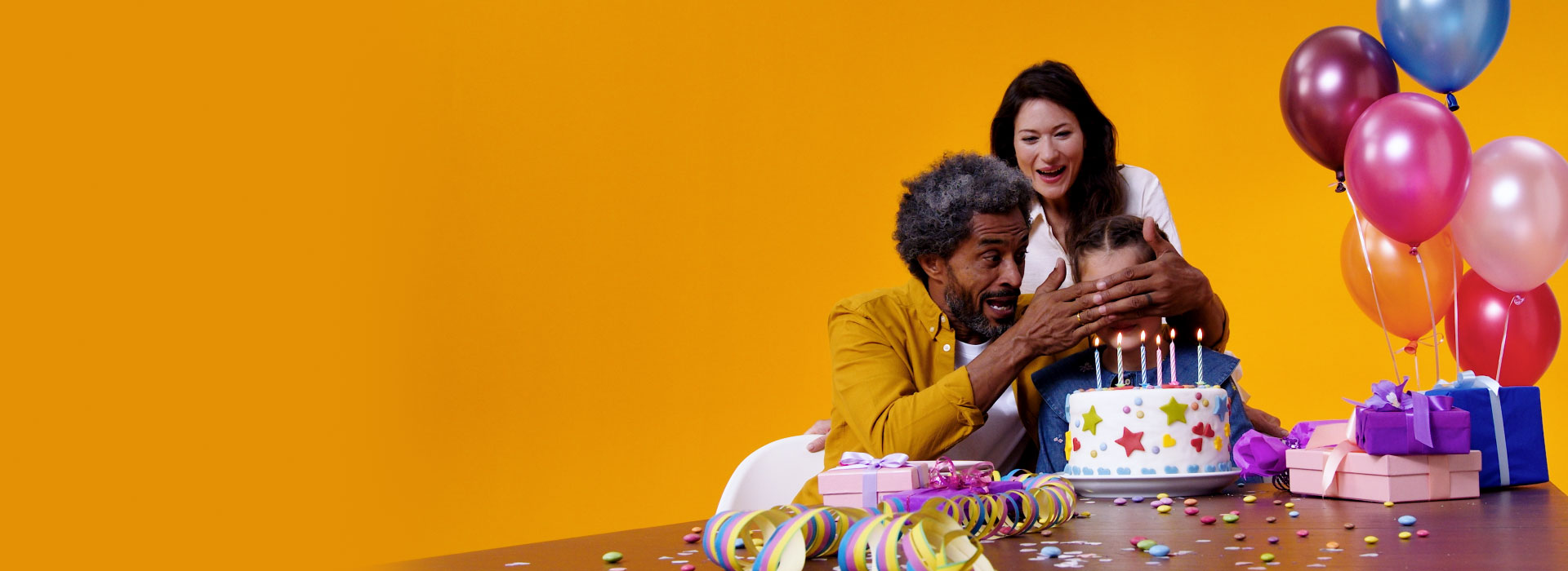 Mężczyzna z aparatami Philips HearLink świętuje z córką urodziny swojej wnuczki. Są balony, ciasto i prezenty